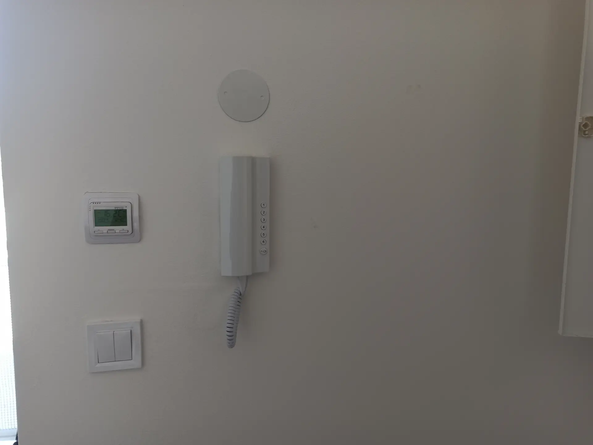 Domovní telefon elegantně umístěný v interiéru vedle termostatu